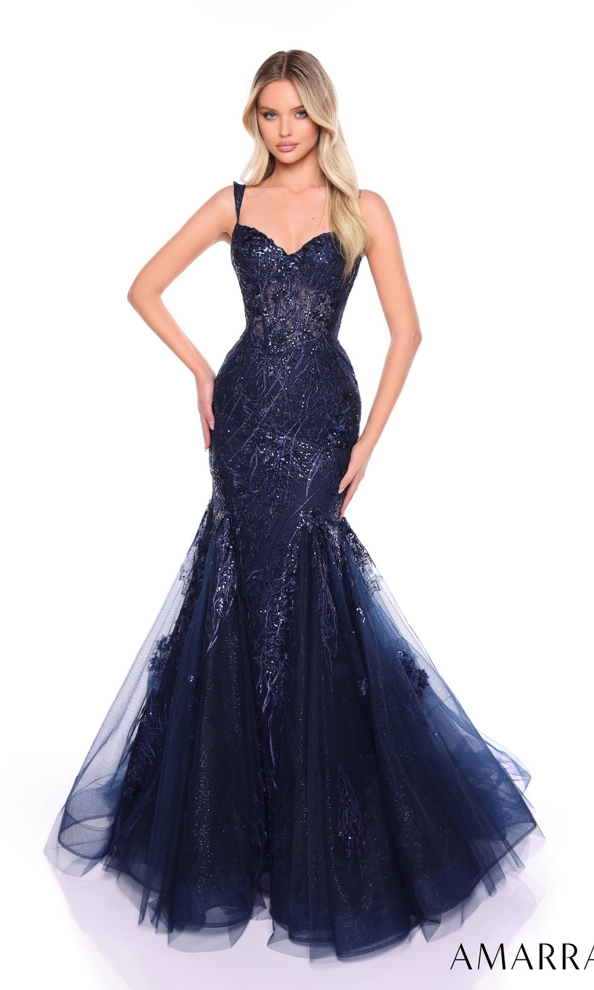 A woman poses against a white background in the Amarra 88132, a dark blue strapless mermaid long formal dress featuring sparkly embellishments and a tulle skirt.